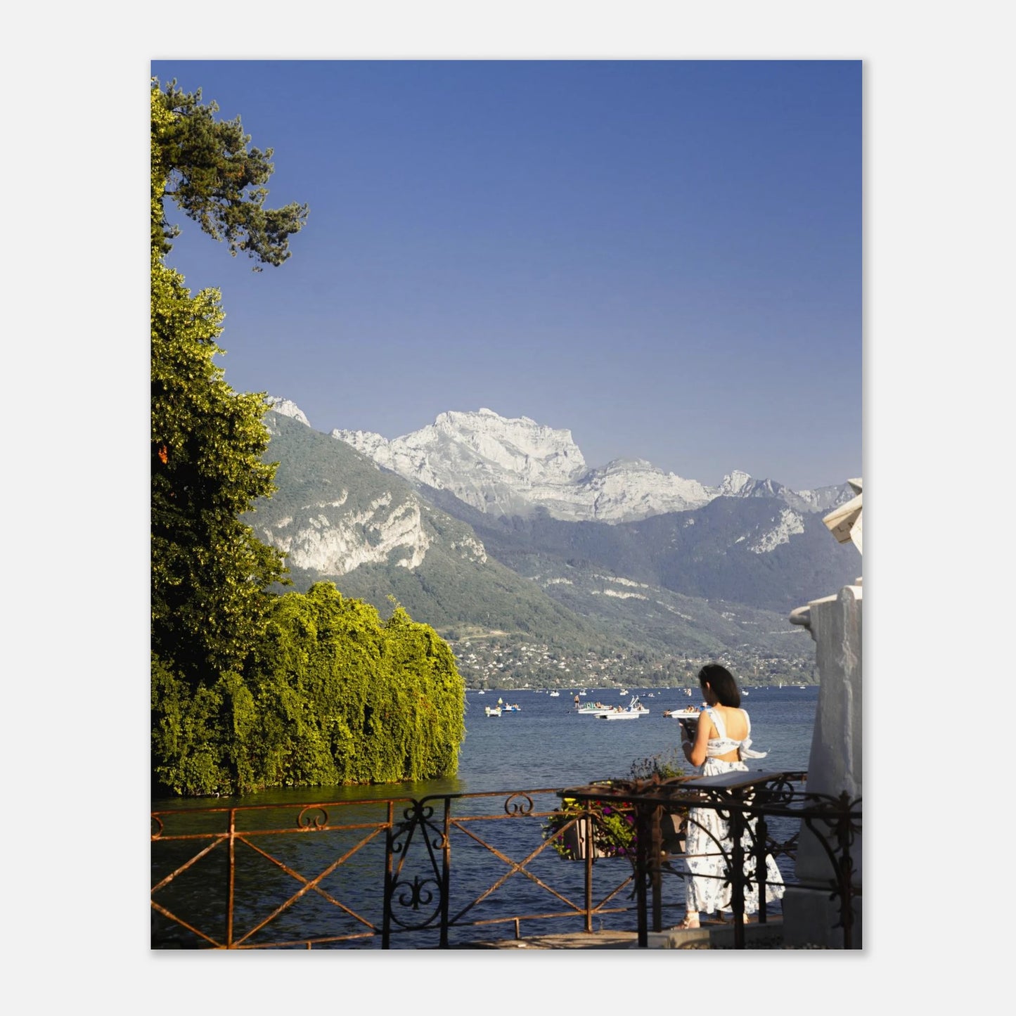 Woman sitting at a table by a lake with mountains in the background