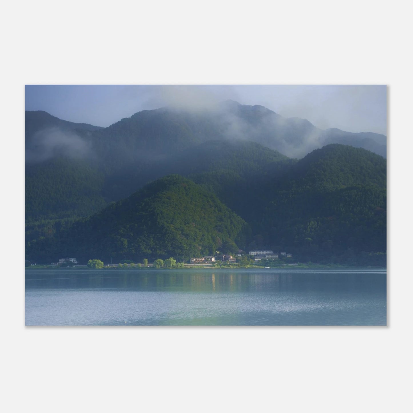 This misty lake mountain landscape wall art print captures serene blue tones and tranquil natural scenery, making it ideal for minimalist home decor. Designed for calming interiors, this fine art nature photography print enhances spaces with peaceful lake reflections, foggy mountain layers, and soft atmospheric light. A perfect choice for those seeking calming wall art, nature-inspired decor, or serene landscape prints for modern homes.