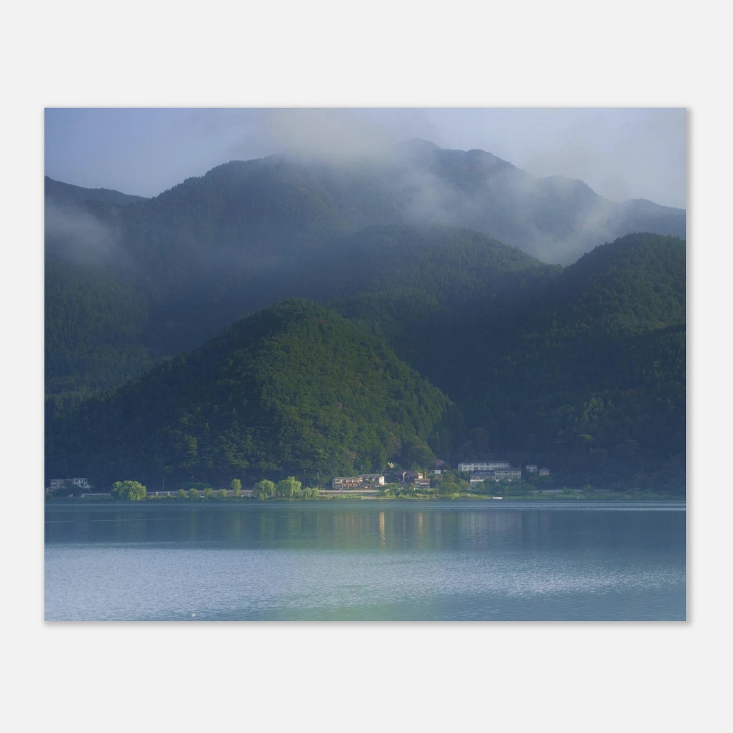 This misty lake mountain landscape wall art print captures serene blue tones and tranquil natural scenery, making it ideal for minimalist home decor. Designed for calming interiors, this fine art nature photography print enhances spaces with peaceful lake reflections, foggy mountain layers, and soft atmospheric light. A perfect choice for those seeking calming wall art, nature-inspired decor, or serene landscape prints for modern homes.