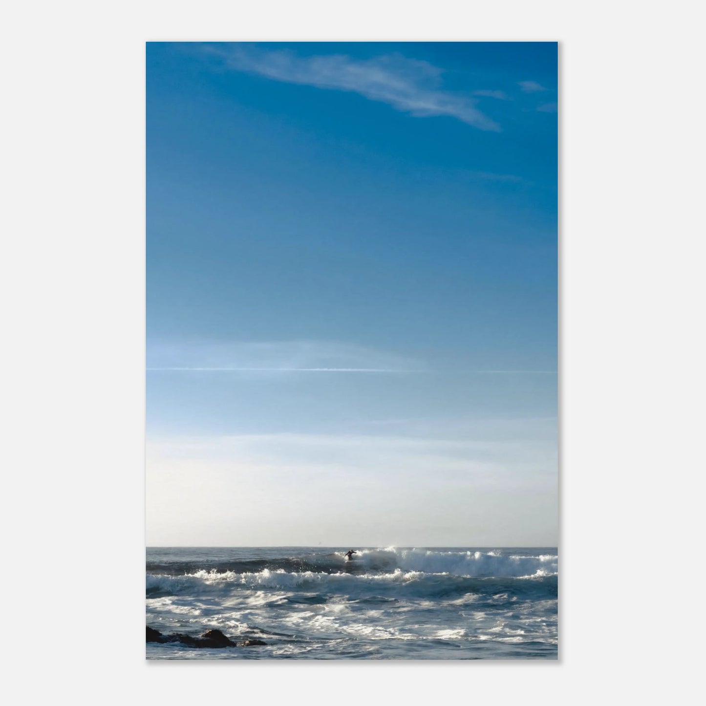 This minimalist ocean photography print features a serene blue seascape with a distant surfer, making it ideal for coastal wall art, calm interior design, and modern minimalist decor. Designed for those seeking premium fine art prints with soft blue tones, it enhances living rooms, bedrooms, and office spaces with a sense of tranquility and refined simplicity.