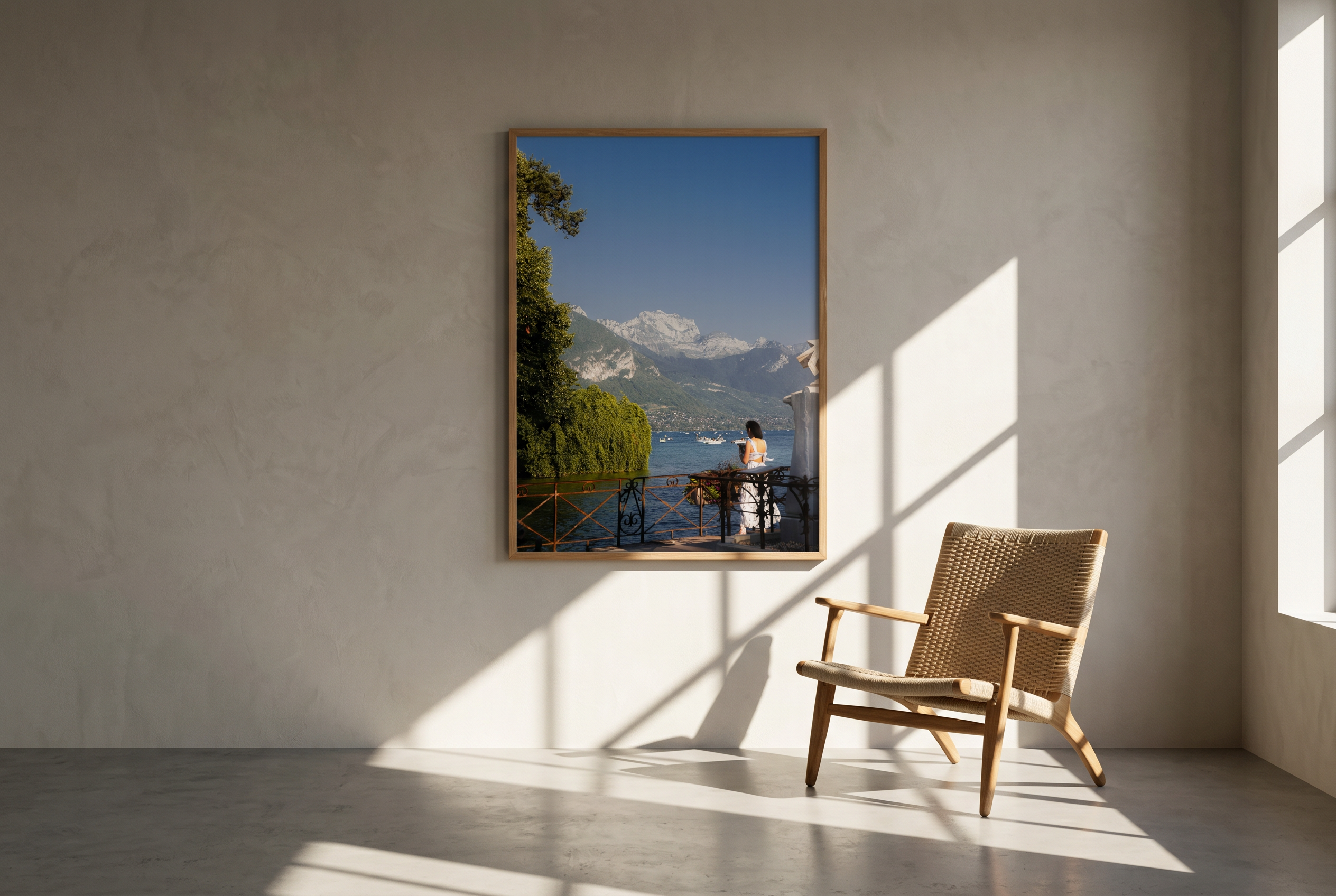 Framed artwork of a scenic landscape with mountains and a person on a dock, placed on a wall in a room with sunlight casting shadows.